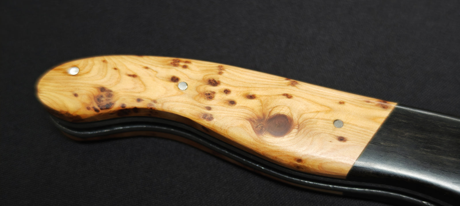 Gros plan sur le manche en bois d'ébène et de genévrier du couteau Laguiole