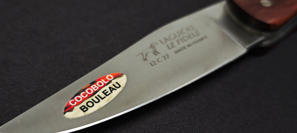 Gros plan sur un couteau Laguiole de chasse avec manche en bouleau, mitres en cocobolo et lame inox