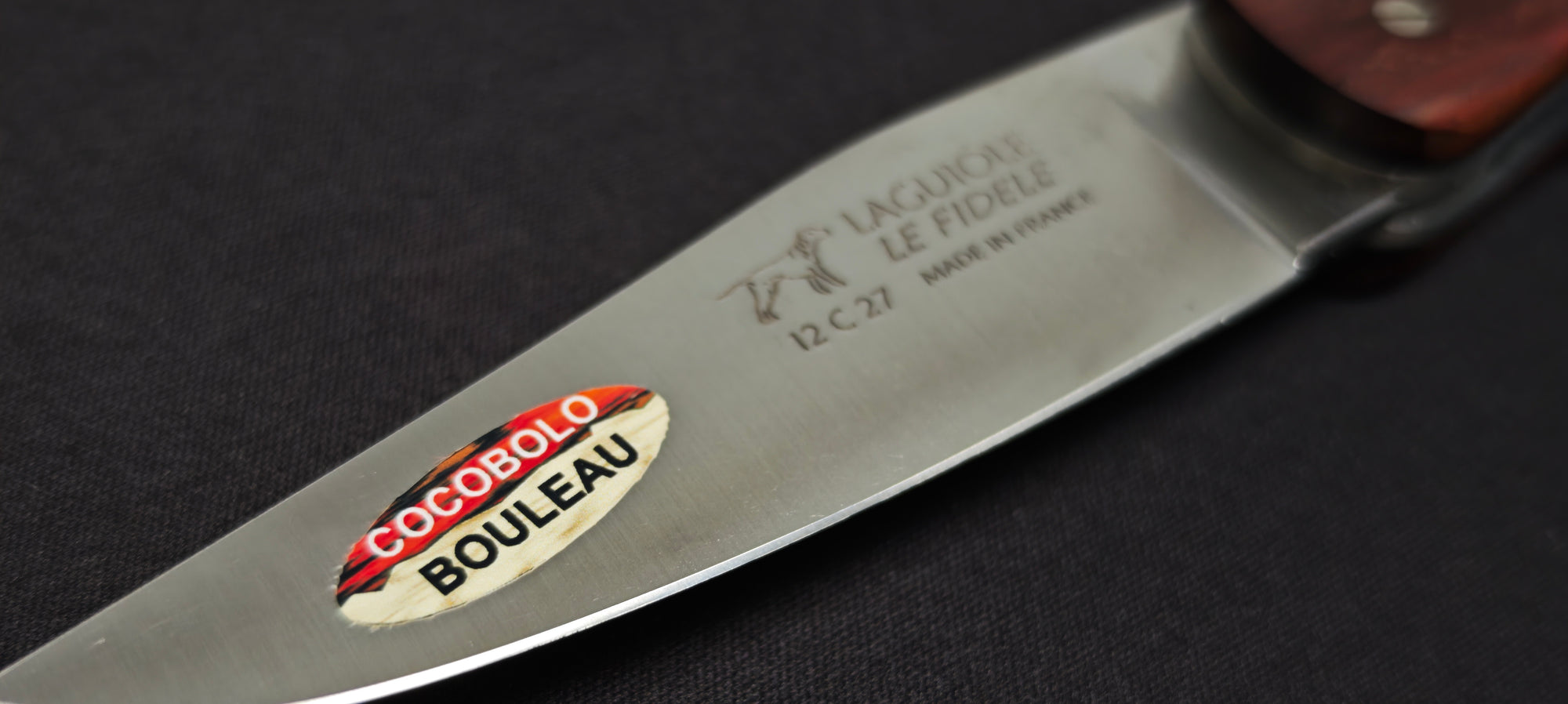 Gros plan sur un couteau Laguiole de chasse avec manche en bouleau, mitres en cocobolo et lame inox