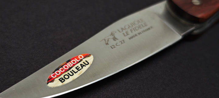 Gros plan sur un couteau Laguiole de chasse avec manche en bouleau, mitres en cocobolo et lame inox