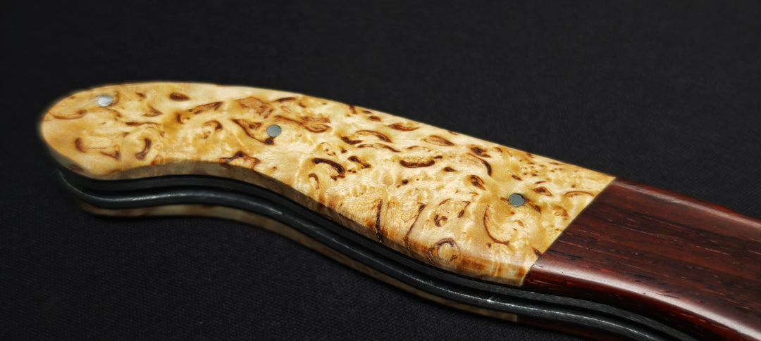 Détail du manche en bouleau et des mitres en cocobolo sur un couteau Laguiole artisanal