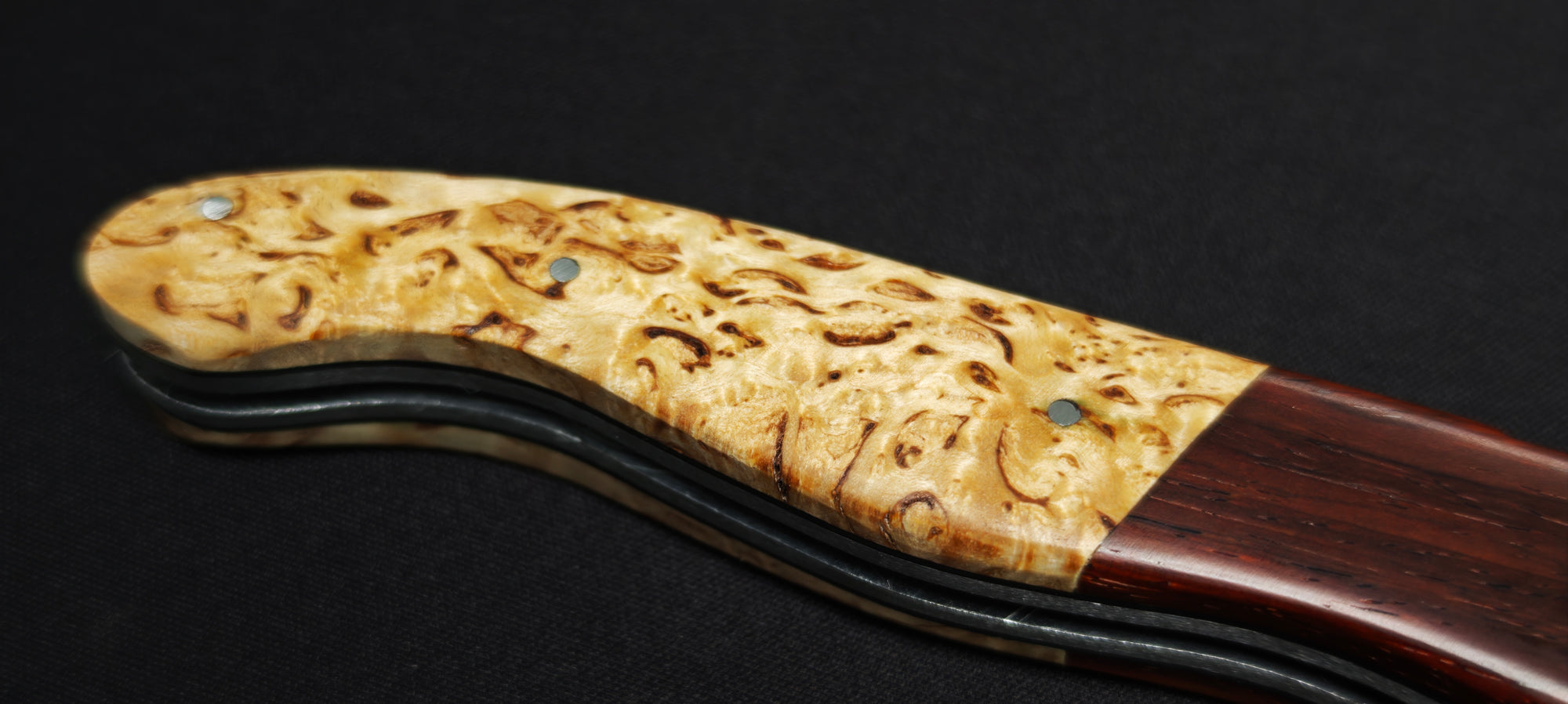 Détail du manche en bouleau et des mitres en cocobolo sur un couteau Laguiole artisanal