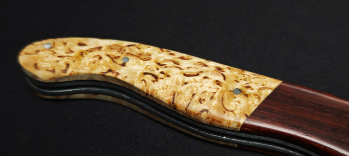 Détail du manche en bouleau et des mitres en cocobolo sur un couteau Laguiole artisanal